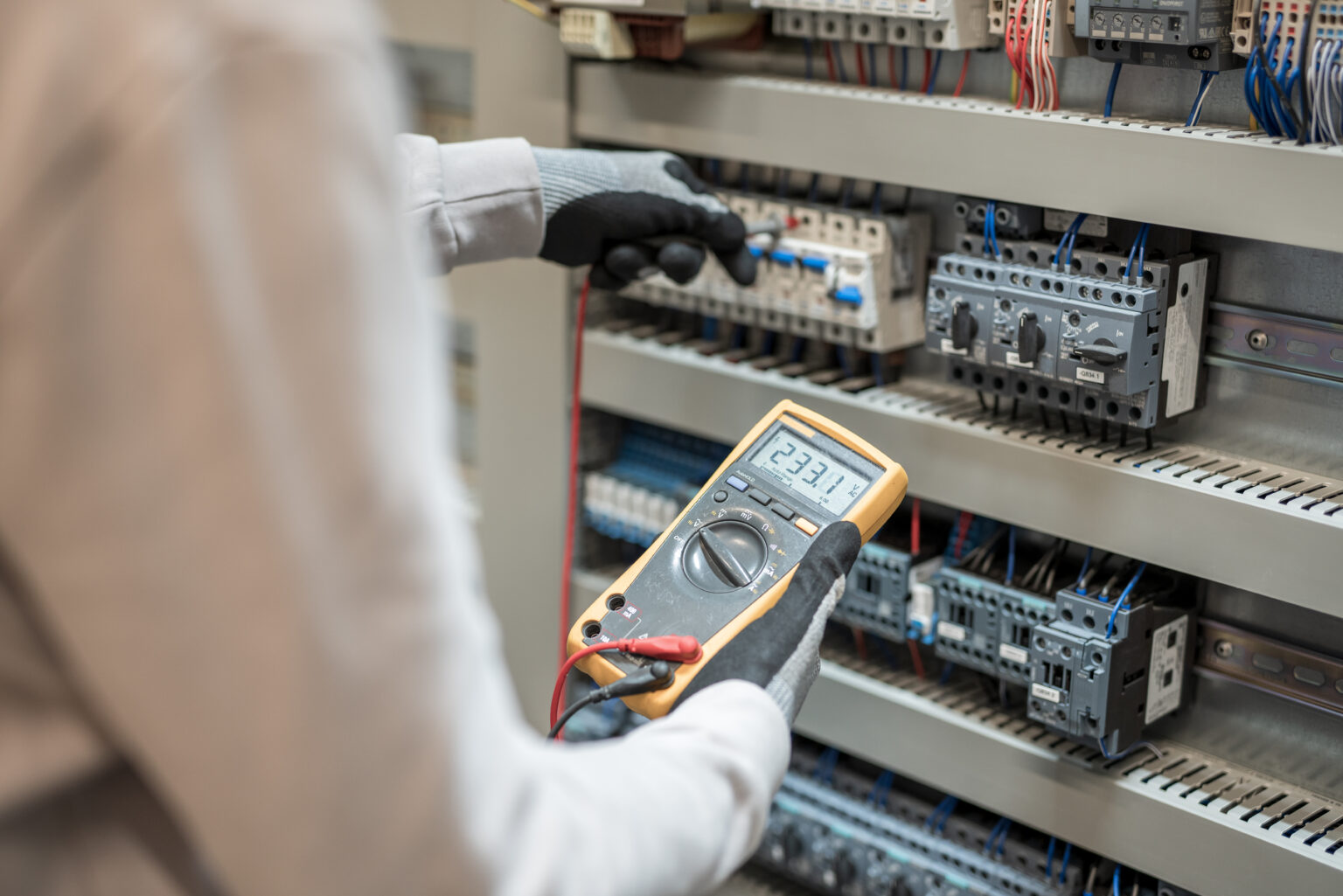 Electricians hands testing current electric in control panel